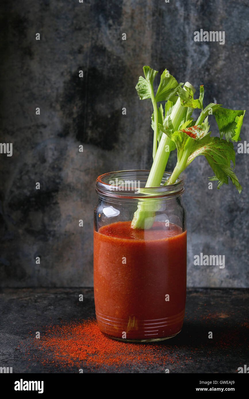 Pot en verre de jus de tomate et le paprika rouge, servi avec branche de céleri et le paprika en poudre sur fond dark iron. Manger sain Banque D'Images