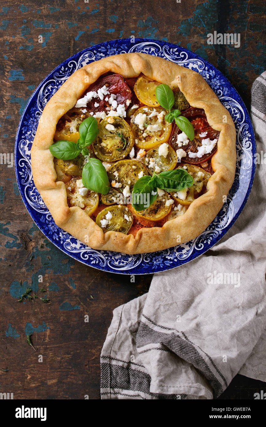 Tarte aux légumes maison ouvrir avec galette tomates colorées, tomates séchées, feta et basilic frais, servi dans l'ornement bleu p Banque D'Images