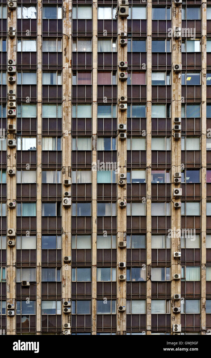 Devant l'ancien bâtiment de bureaux, de verre et de béton, des fenêtres, des stores et de l'air conditioneers Banque D'Images