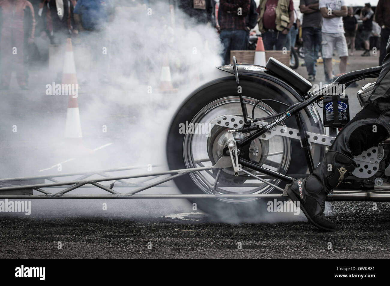 Un pilote moto effectue un burnout, pour réchauffer le pneu, avant une course d'événement. Banque D'Images