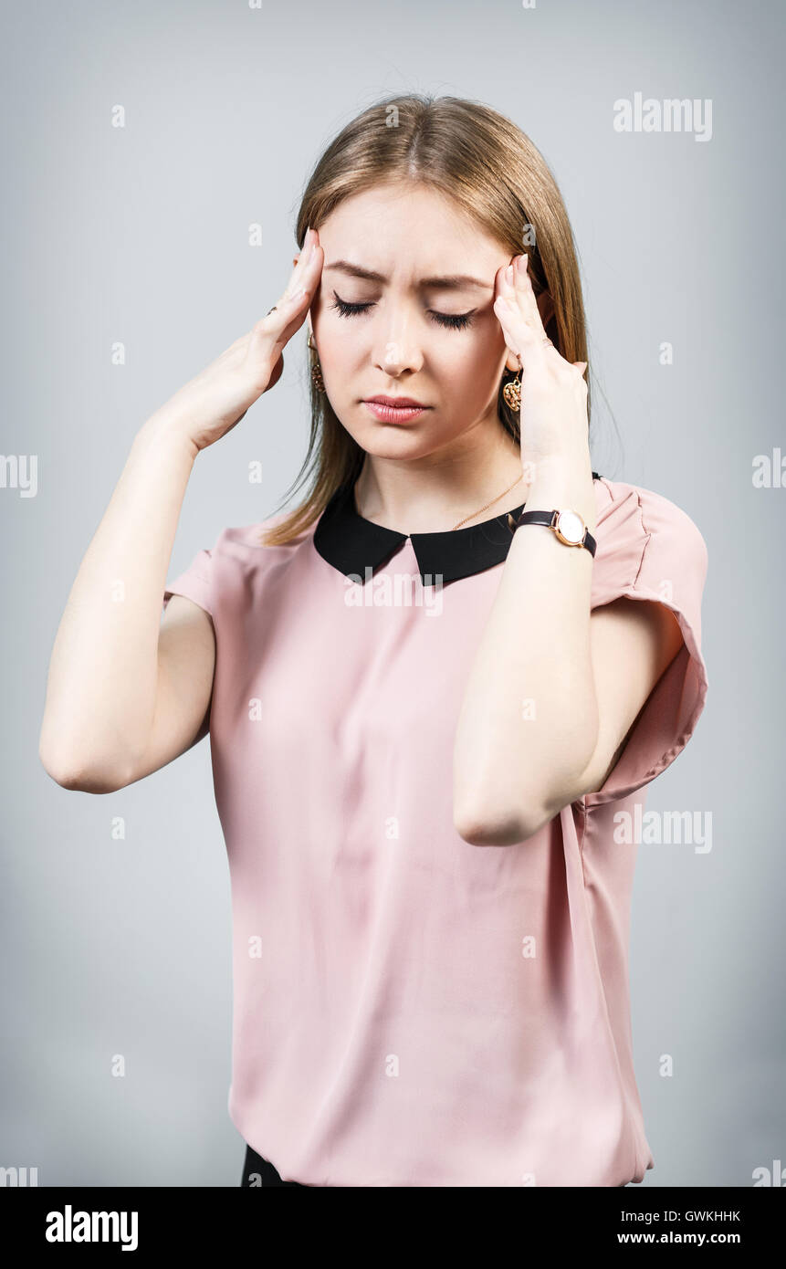 Jeune femme avec des maux de tête sur l'arrière-plan gris Banque D'Images