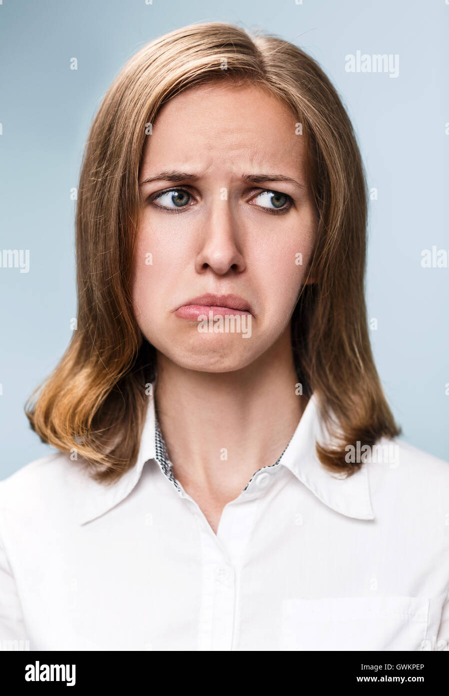 Jeune femme faisant la moue expression sur fond gris Banque D'Images
