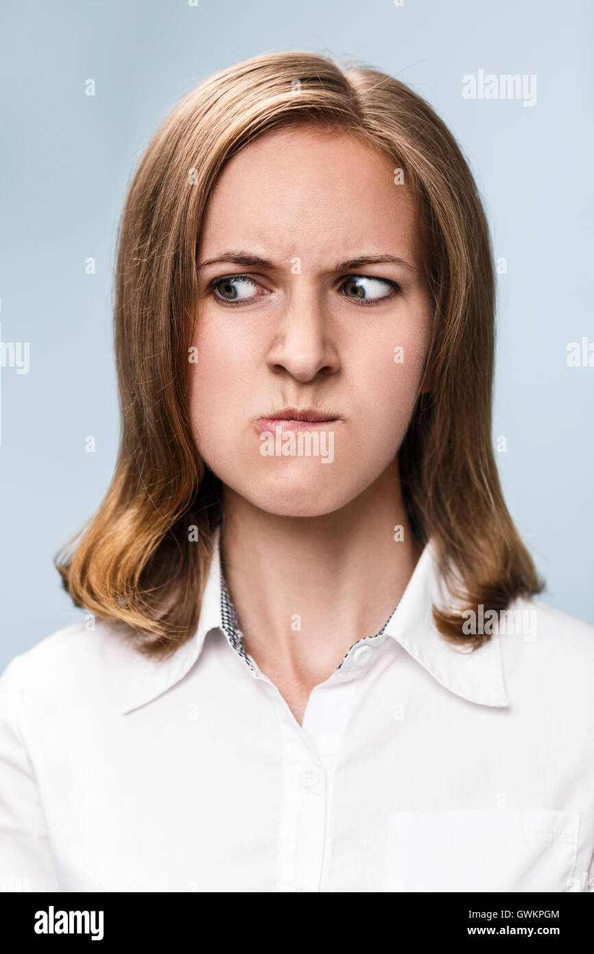 Jeune femme avec très en colère face à l'arrière-plan bleu. Banque D'Images