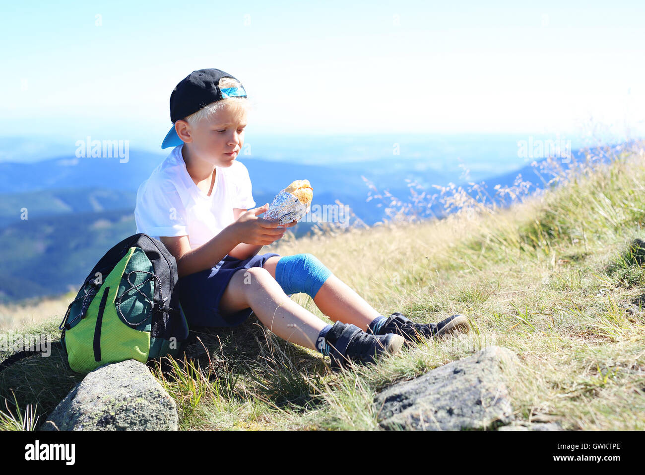 Vacances à la montagne. L'enfant est en train de manger un sandwich sur un sentier de montagne Banque D'Images