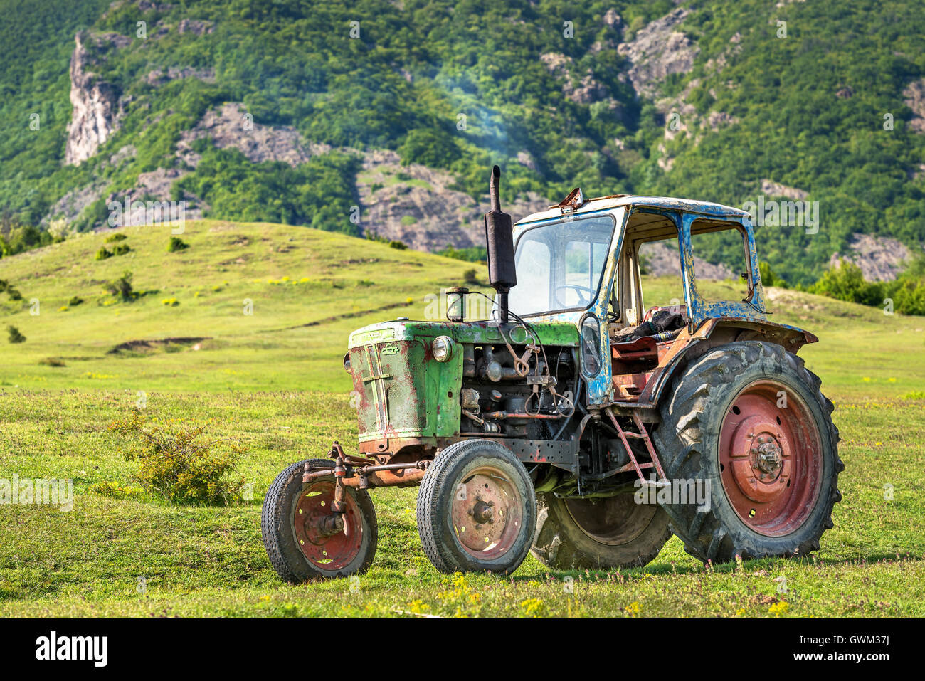 Vieux tracteur rouillé stationné dans la nature. Banque D'Images