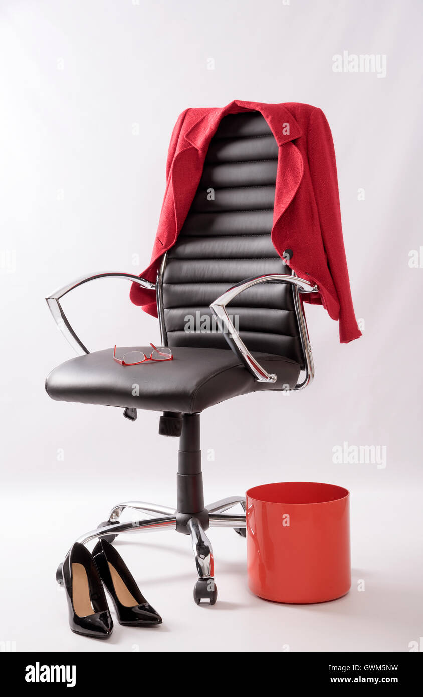Un fauteuil en cuir noir avec un manteau rouge poubelle, hautes chaussures de talon et une paire de lunettes sur le siège Banque D'Images