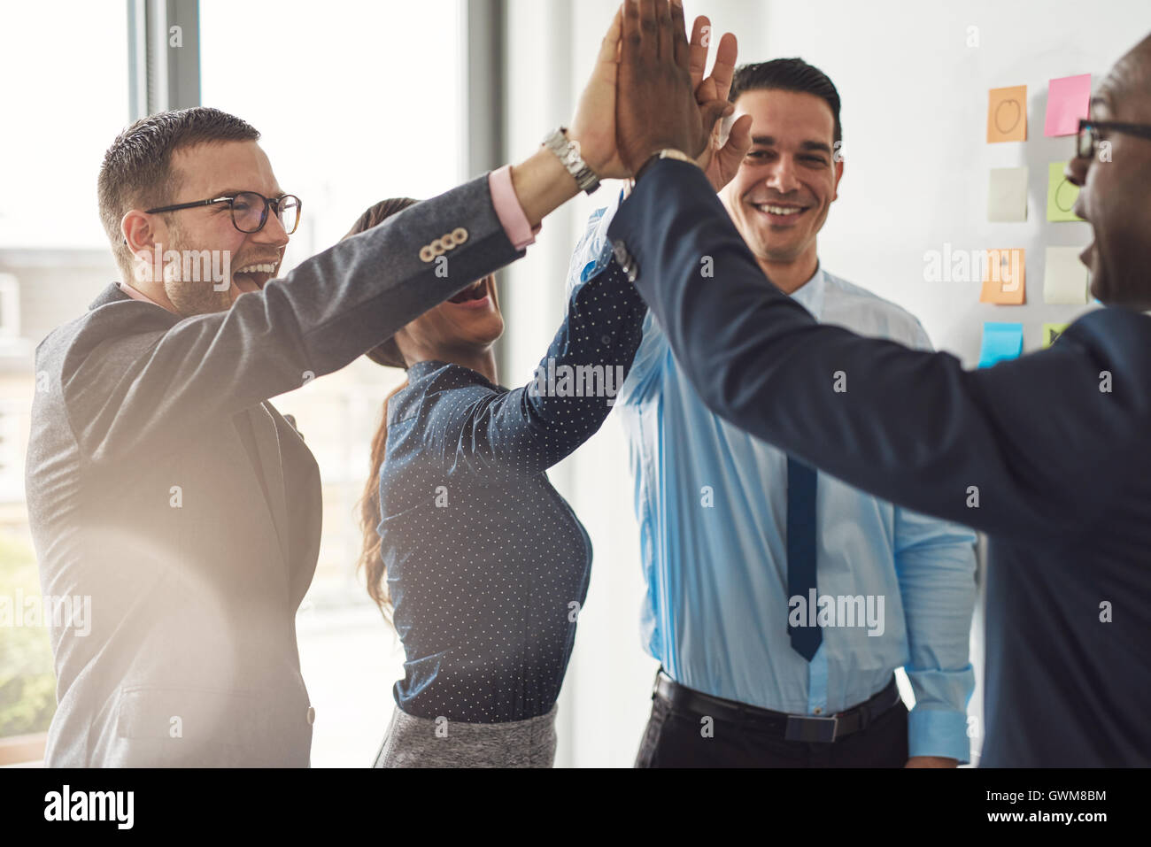 L'équipe entreprise multiraciale réussie heureux donnant une forte fives geste comme ils rient et applaudir leur succès Banque D'Images