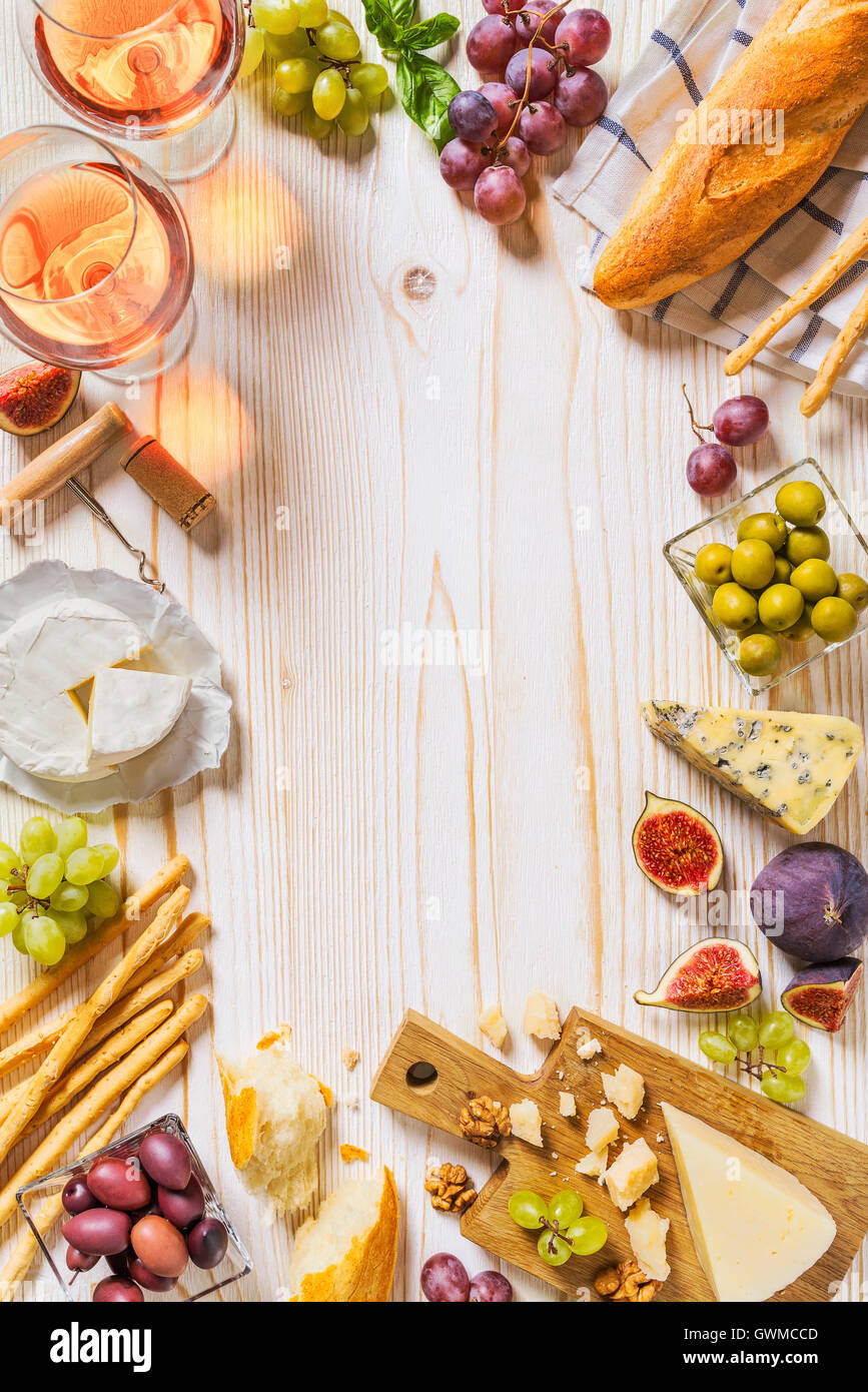 Différents types de fromages, du vin, des baguettes et des fruits on white Banque D'Images