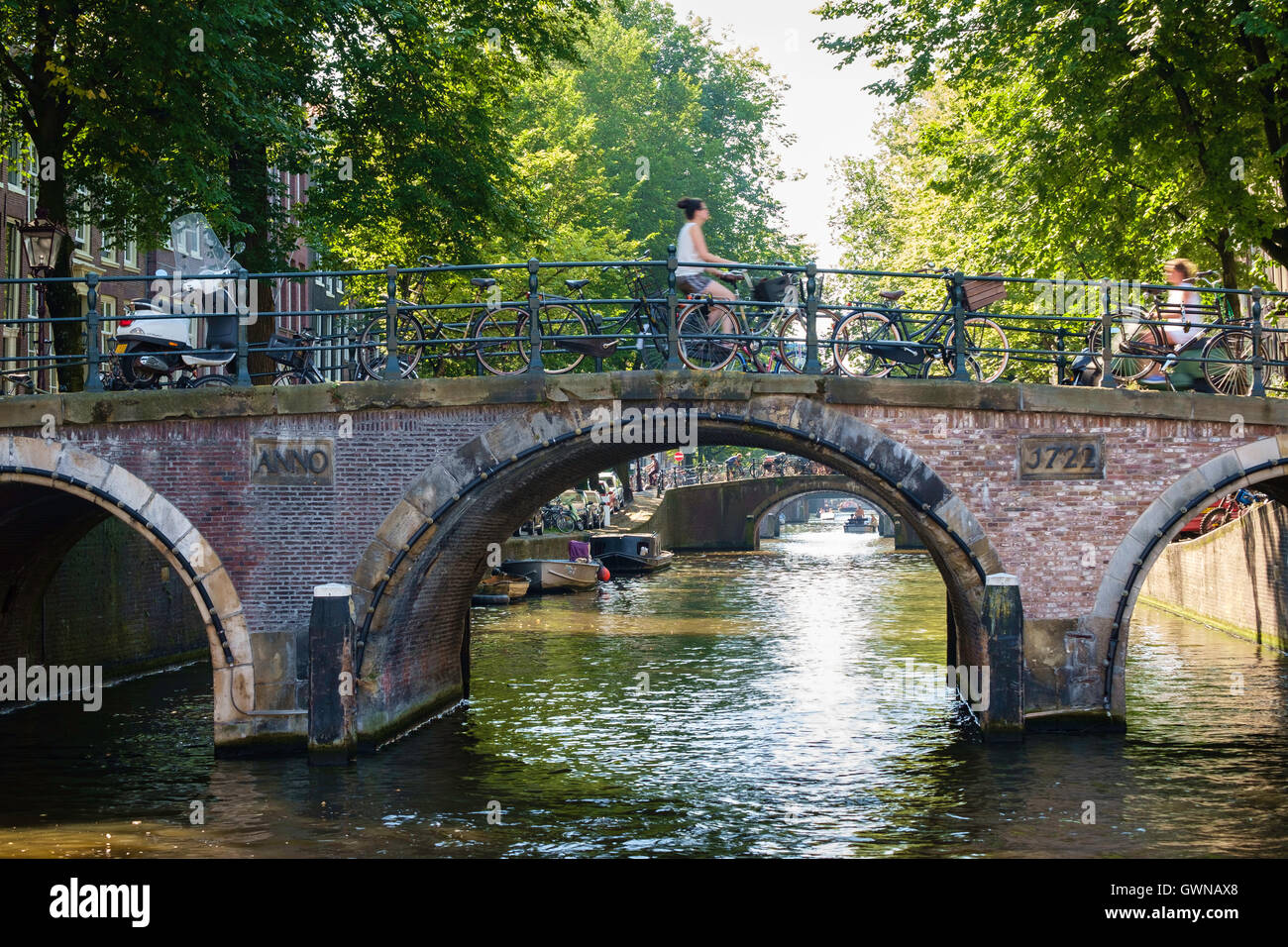 Les cyclistes traversent un soleil d'été pont-canal à Amsterdam. Banque D'Images