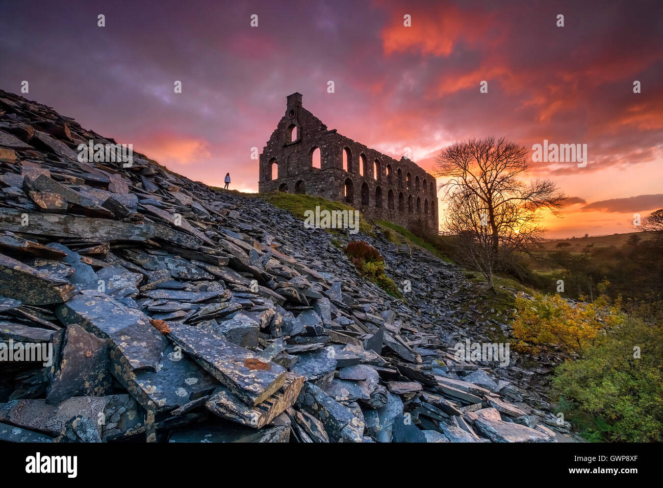 Une Silhouette solitaire se trouve à Ynys y Pandy Moulin ardoise désaffectées, Cwmystradllyn au coucher du soleil, Parc National de Snowdonia, le Nord du Pays de Galles, Royaume-Uni Banque D'Images