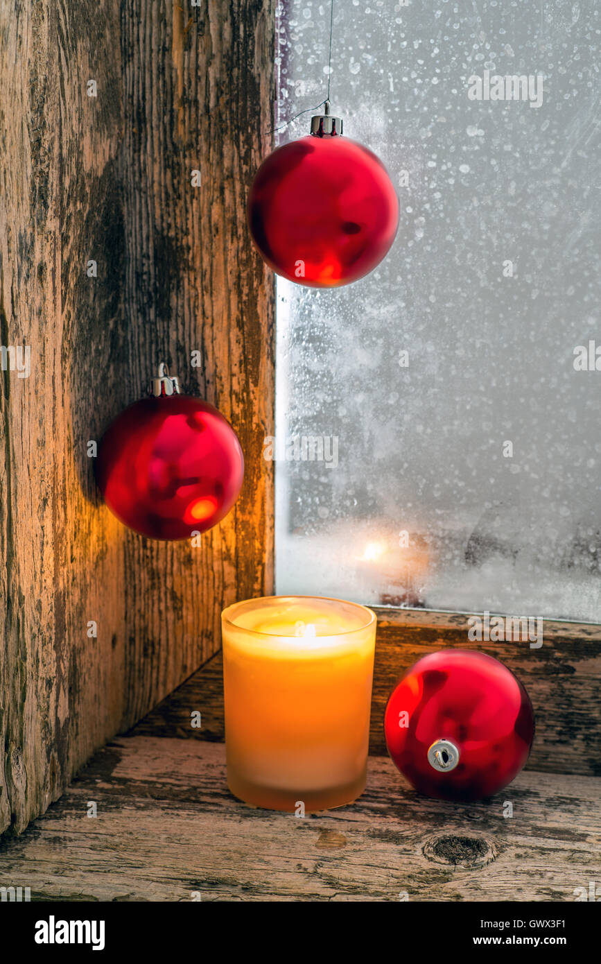 Bougie allumée et des boules de Noël sur le rebord d'une ancienne fenêtre avec verre dépoli Banque D'Images