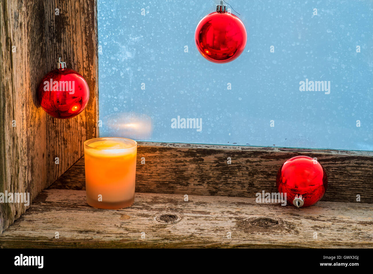 Bougie allumée et des boules de Noël sur le rebord d'une ancienne fenêtre avec verre dépoli Banque D'Images