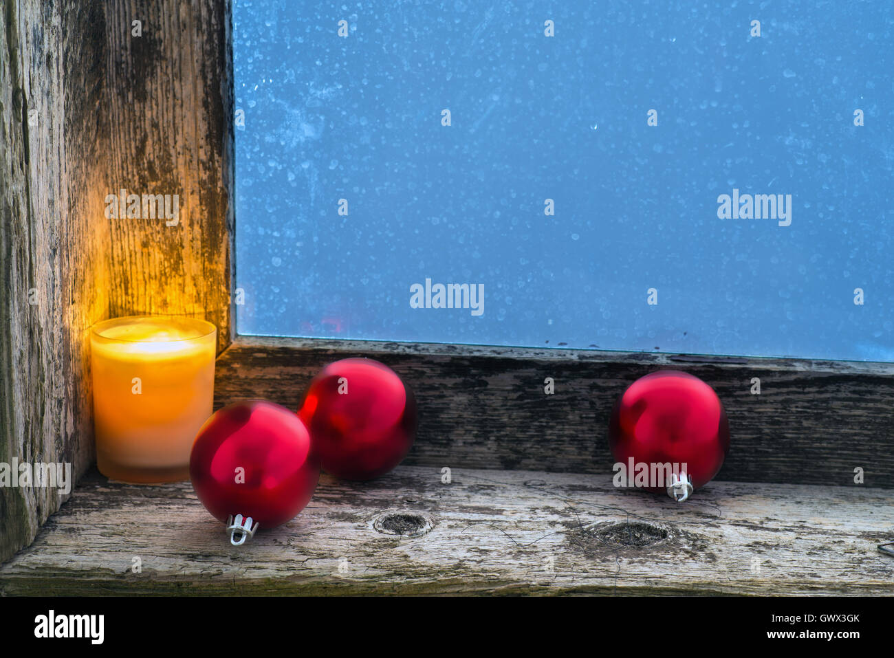 Bougie allumée et des boules de Noël sur le rebord d'une ancienne fenêtre avec verre dépoli. Copy space Banque D'Images