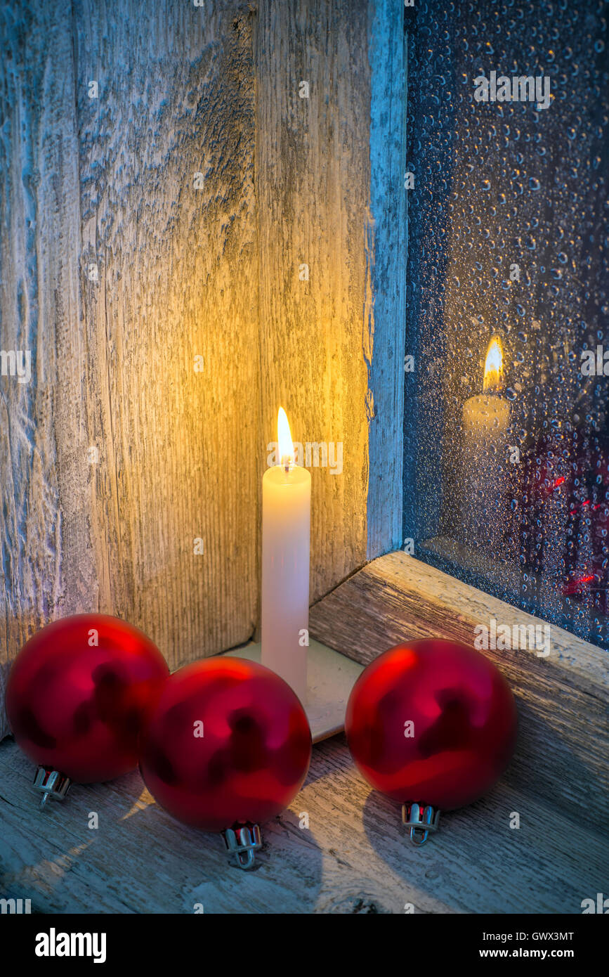 Bougie brûlante et ornements de Noël dans une ancienne fenêtre avec verre  humide Photo Stock - Alamy