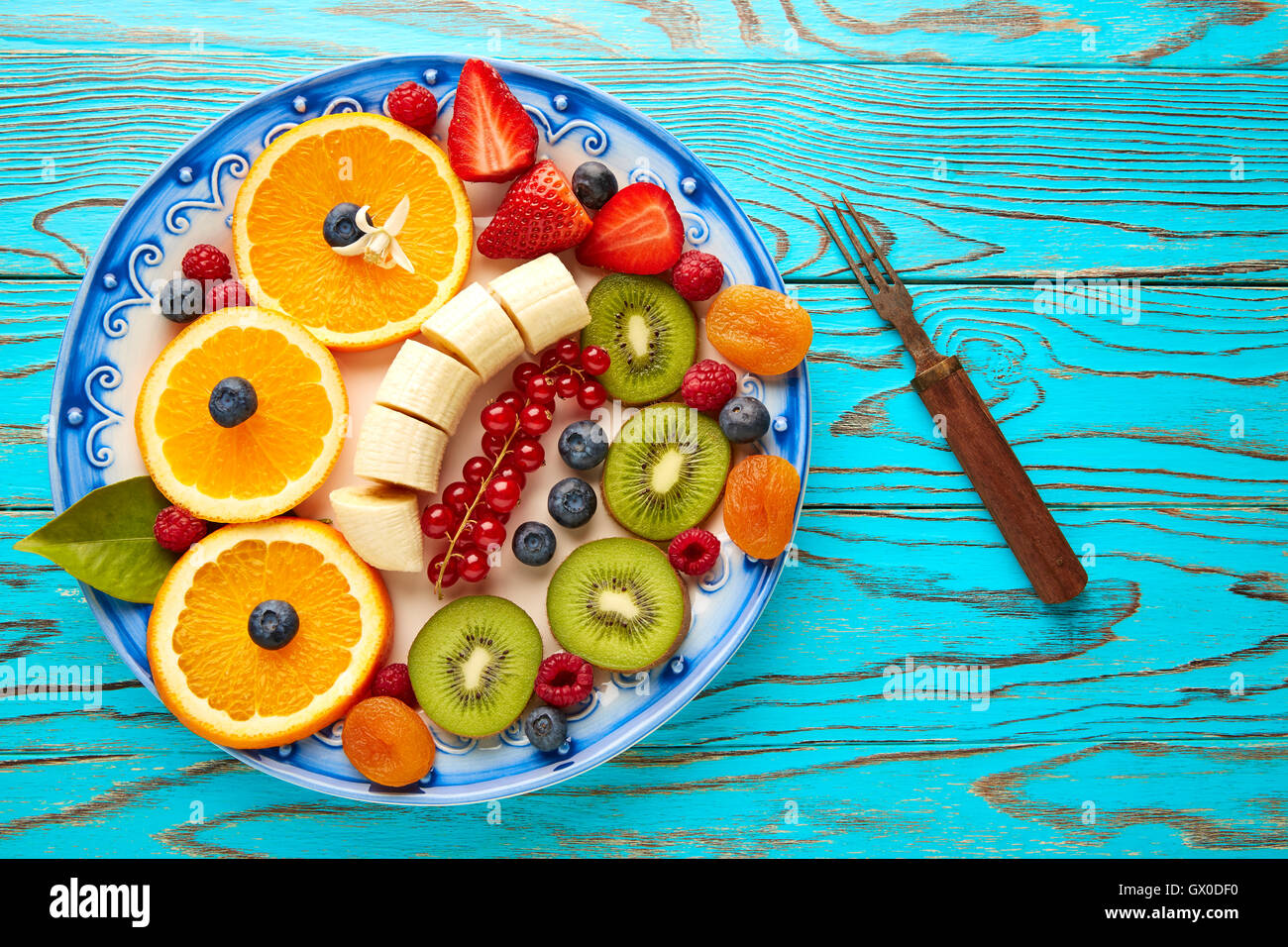 Petit-déjeuner salade de fruits banane orange kiwi berries ow table turquoise Banque D'Images