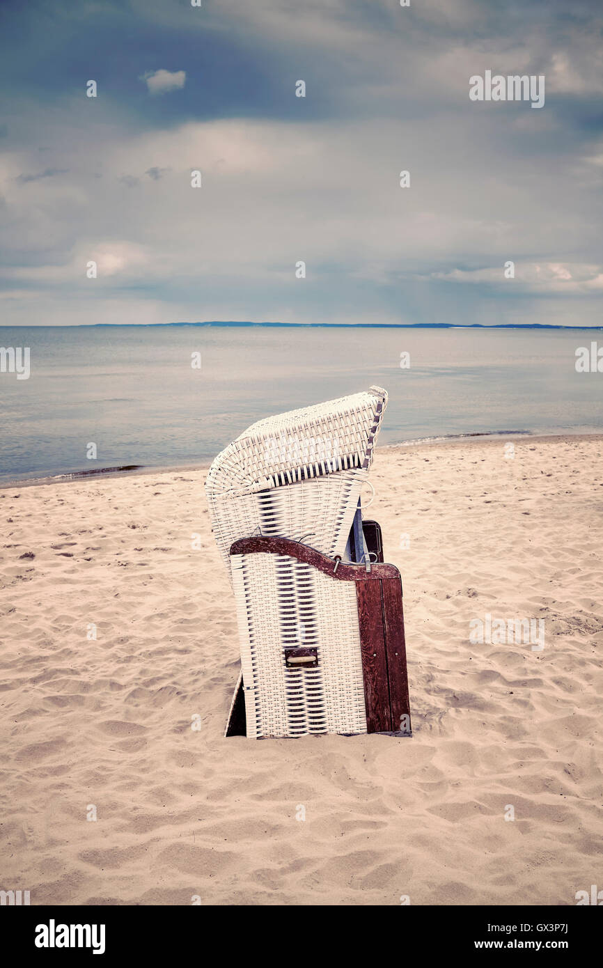 Panier en osier à capuchon stylisé rétro chaise sur une plage vide. Banque D'Images