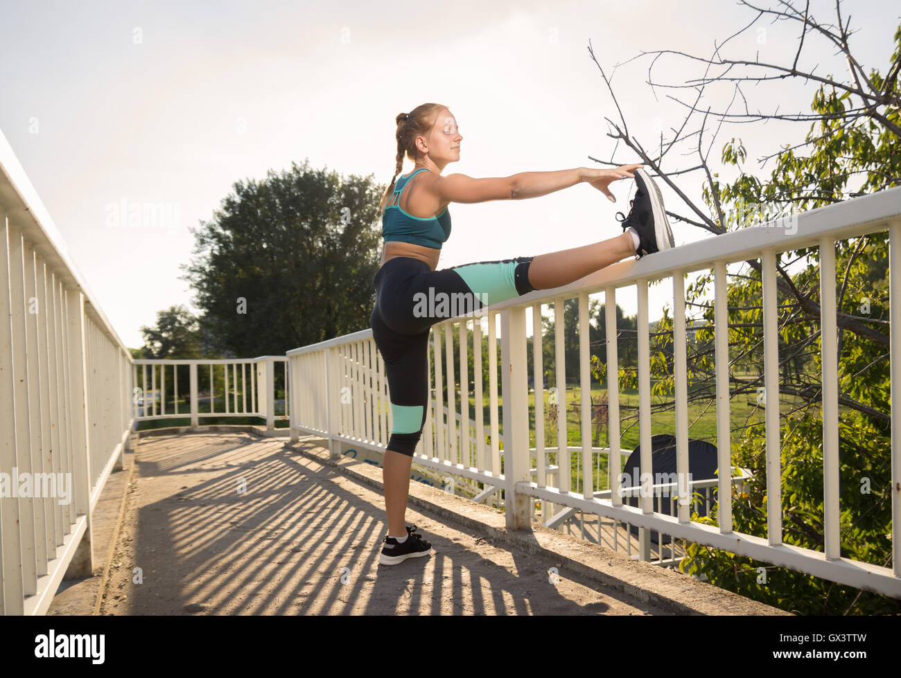 Teenage girl stretching outdoors jambes journée ensoleillée,-bra Banque D'Images
