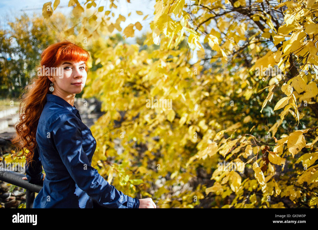 Belle femme en automne parc avec feuilles jaune arrière-plan. Concept de la chaleur, l'énergie positive, profiter de la nature. Banque D'Images
