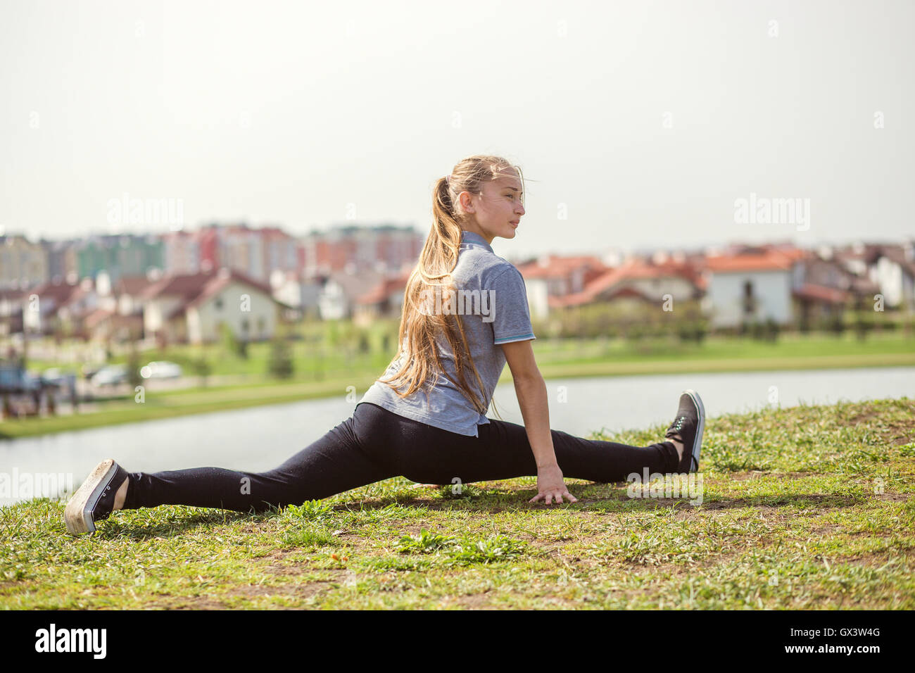 Happy young girl doing stretching exercises en parc d'été Banque D'Images