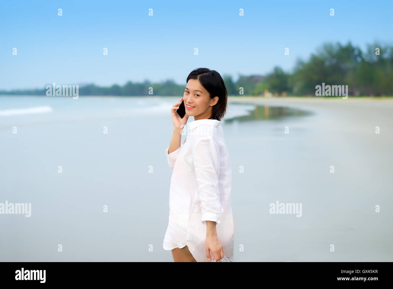 Asian girl parler au téléphone à une plage locations Banque D'Images