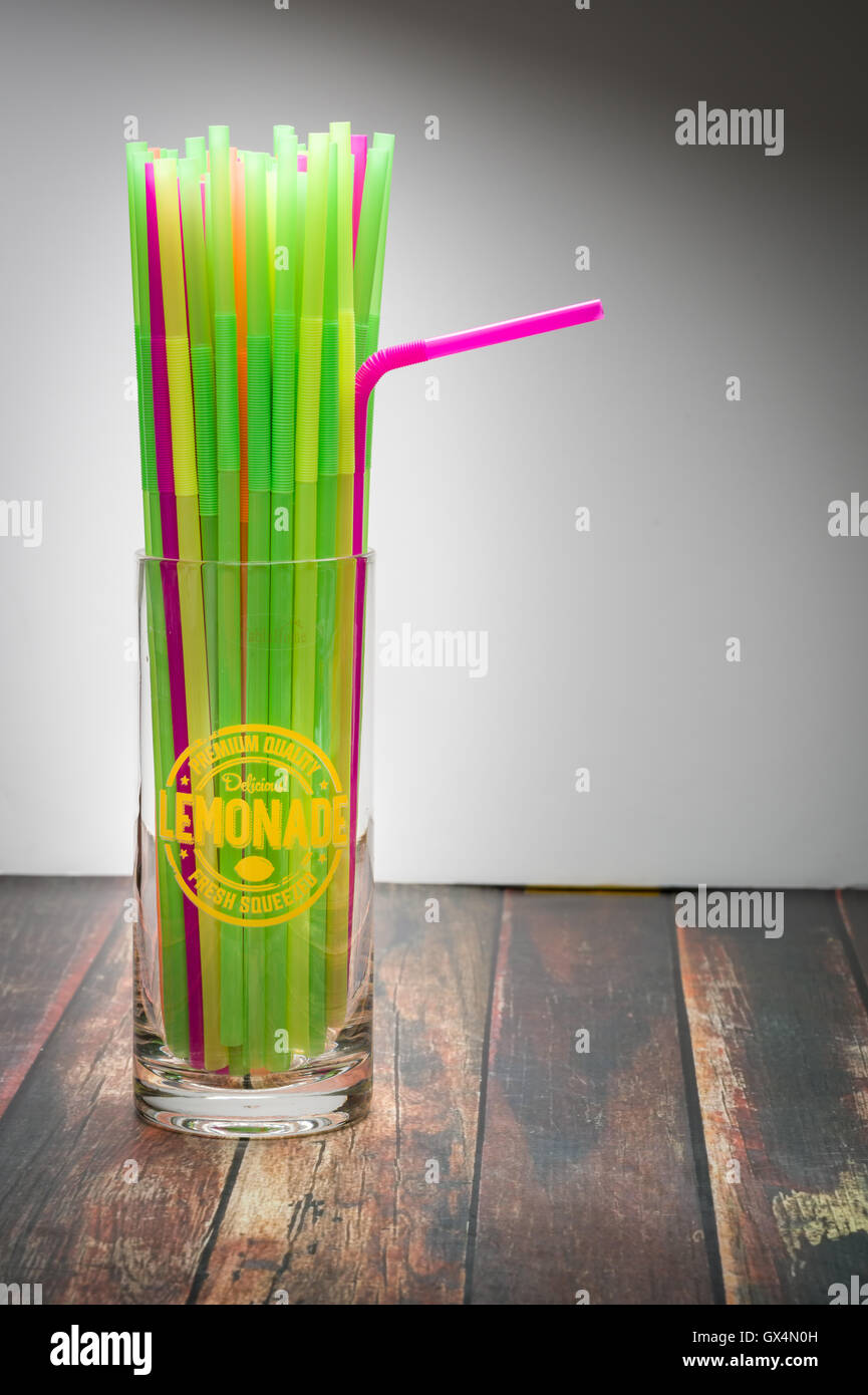 Pailles multicolores dans un verre de limonade sur la surface du bois Banque D'Images