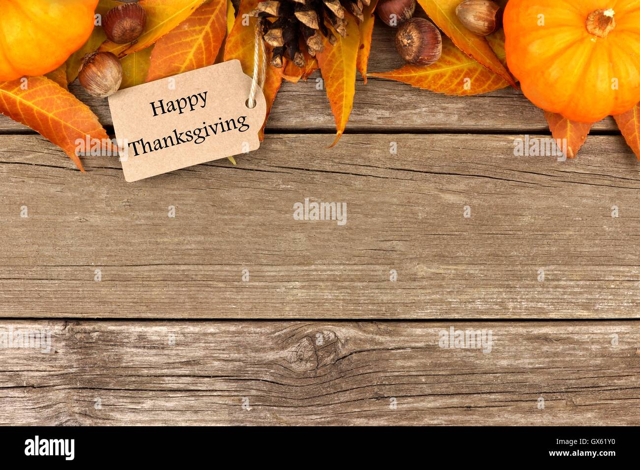 Joyeux Thanksgiving tag avec bordure supérieure de citrouilles d'automne, les feuilles et les noix sur un fond de bois rustique Banque D'Images