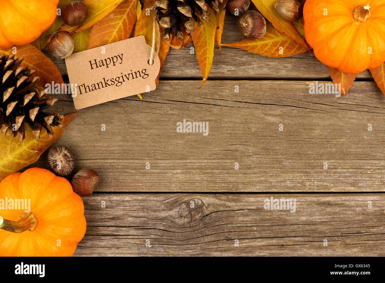Joyeux Thanksgiving gift tag with corner border de feuilles colorées et des citrouilles sur un fond de bois rustique Banque D'Images