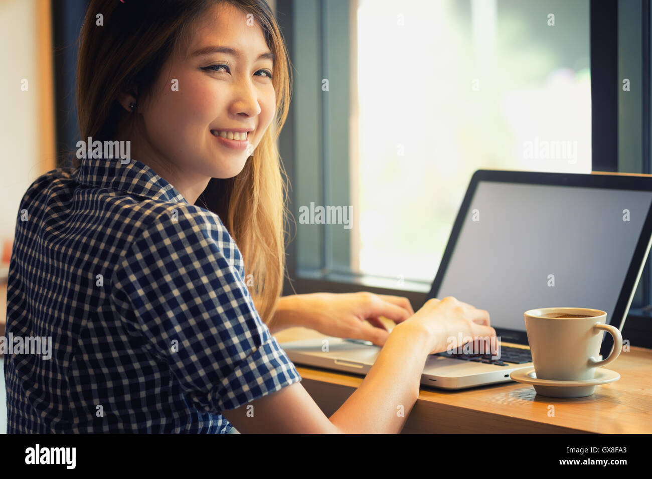 Belle Asie en utilisant son ordinateur portable et de boire tasse de café en café, de vacances concept. Banque D'Images