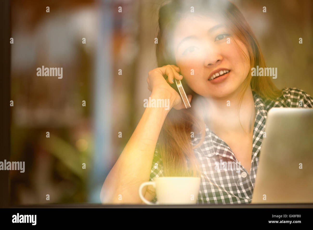 Portrait de l'Asie jolie femme parlant au téléphone tout en restant assis dans un café et profiter du café, du concept des vacances. Banque D'Images
