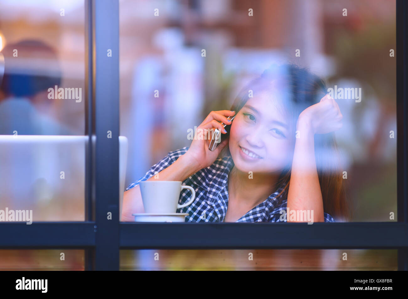 Portrait de l'Asie joli sourire femme parlant au téléphone tout en restant assis dans un café et profiter du café, du concept des vacances. Banque D'Images