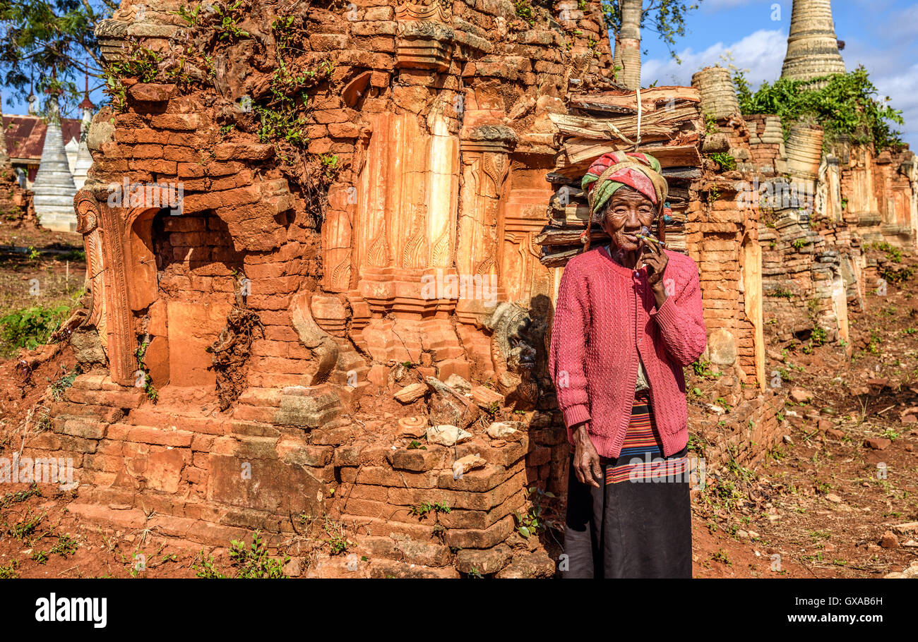 Vieille Femme ridée fume un cigare cheroot autour des temples en ruines dans la ville antique de Ava, également appelé Inwa Banque D'Images