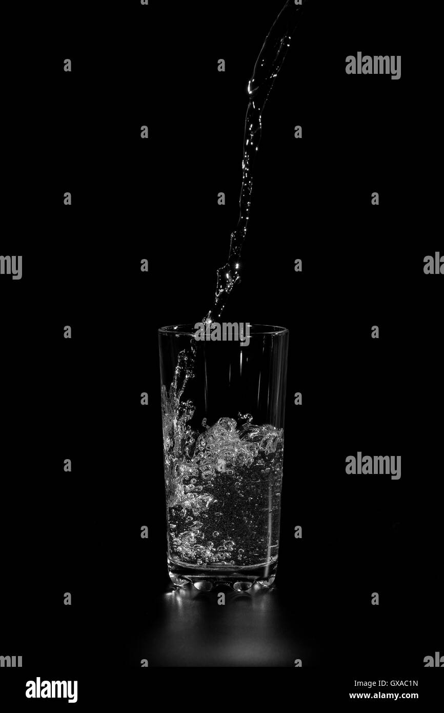 Minéral pur l'eau versée dans un bécher en verre sur fond noir Banque D'Images