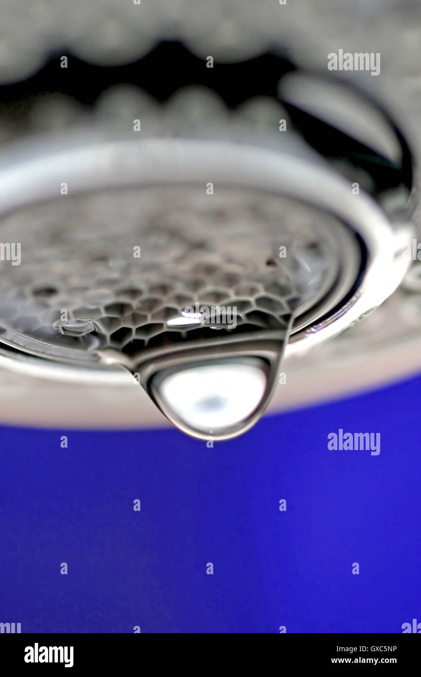 Une macro d'un robinet robinet blanc / dégoulinant de fond bleu. Banque D'Images