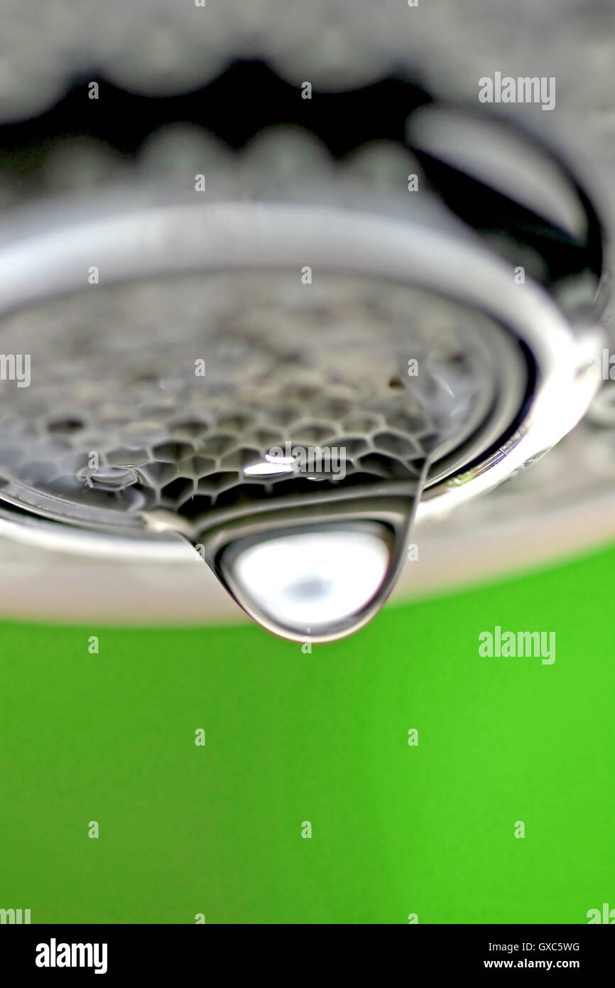 Une macro d'un robinet robinet blanc / dégoulinant de fond vert. Banque D'Images