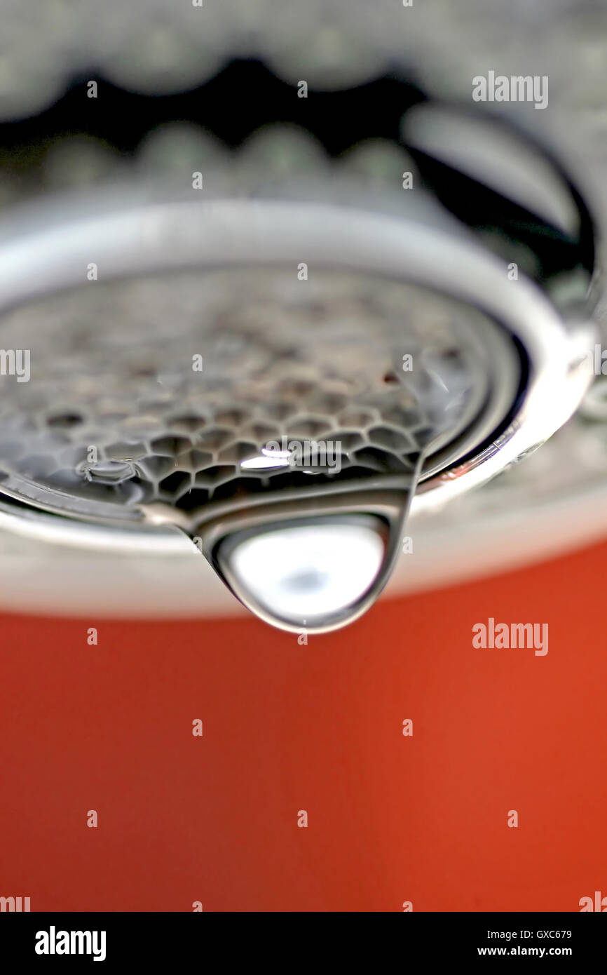 Une macro d'un robinet robinet blanc / dégoulinant de fond rouge. Banque D'Images
