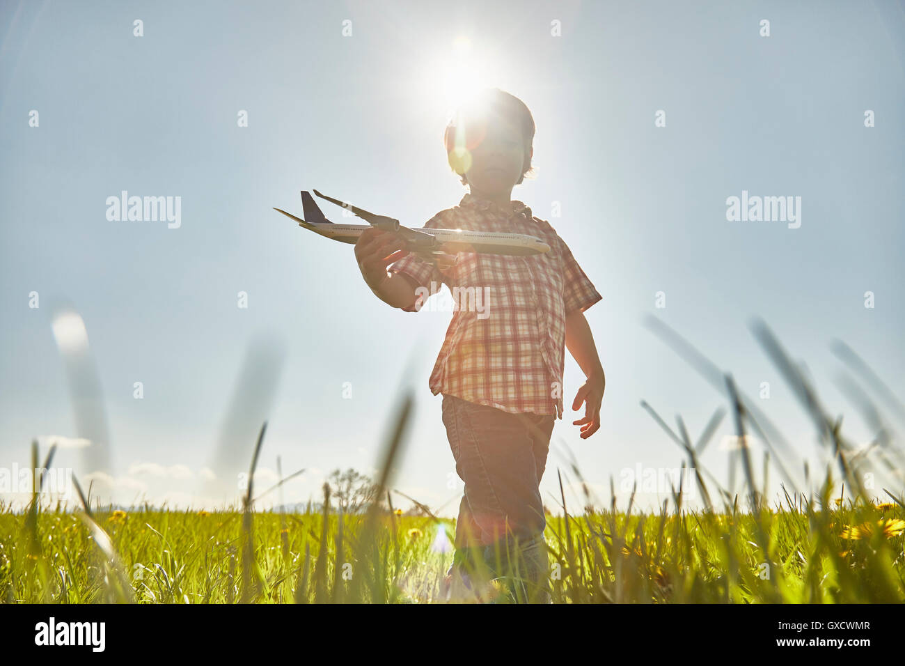 Boy in sunlit domaine Playing with toy airplane Banque D'Images