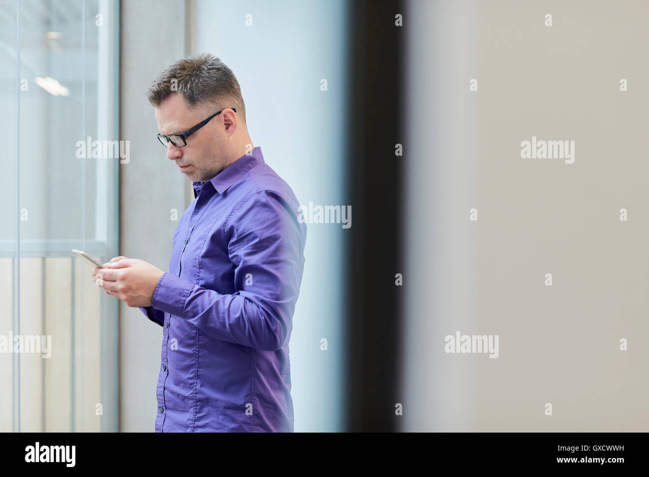 Designer hommes lecture texte smartphone in design studio Banque D'Images