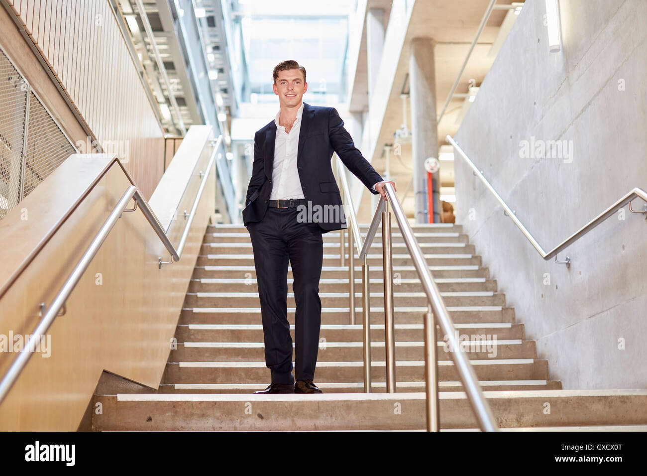 Portrait of young businessman standing on office stairway Banque D'Images