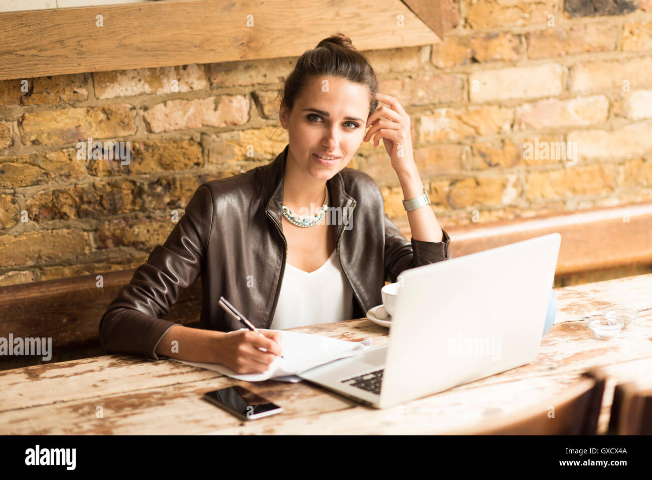 Portrait of young businesswoman making notes in cafe Banque D'Images