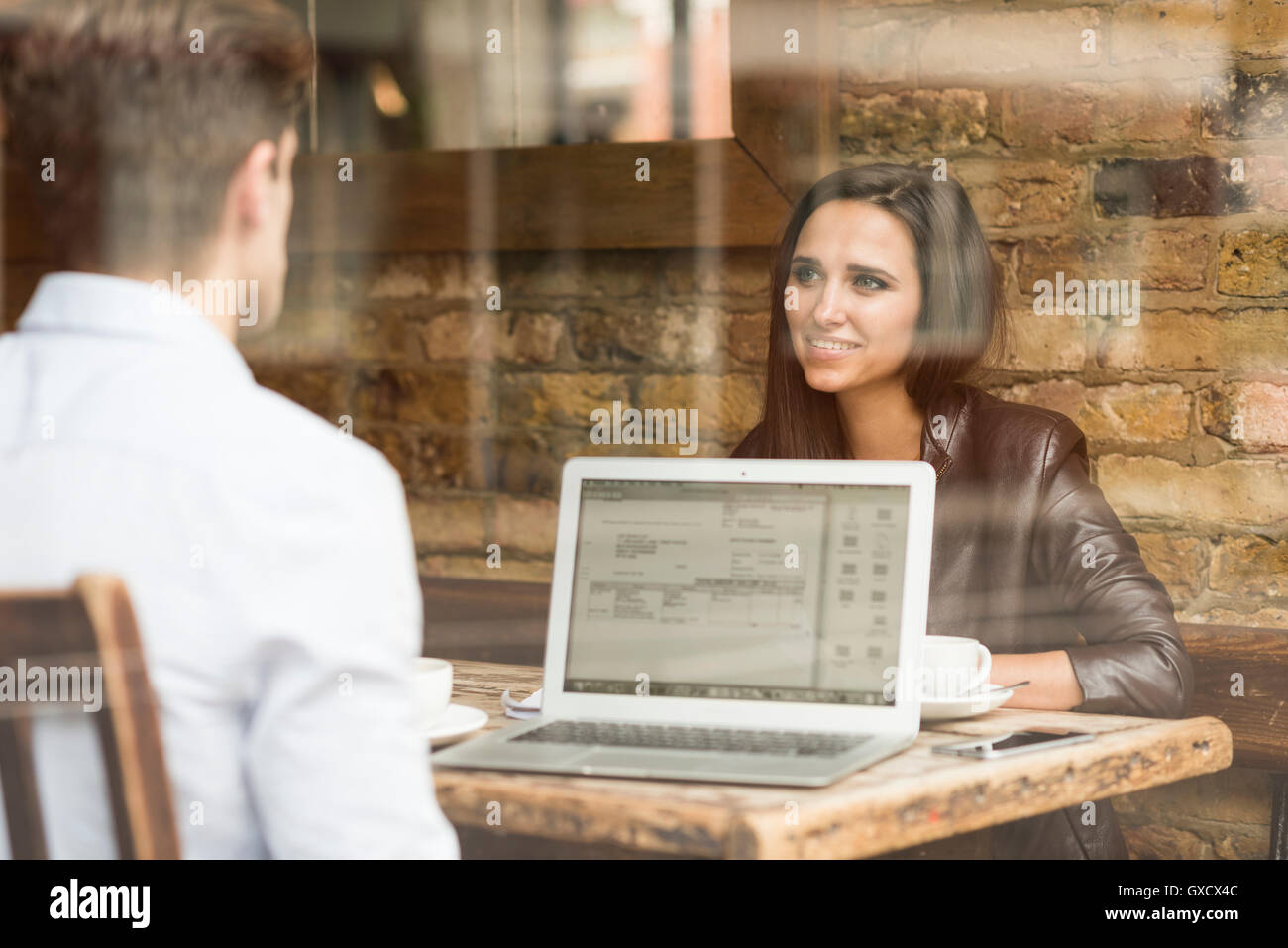 Young businessman and woman working with laptop and talking in cafe Banque D'Images