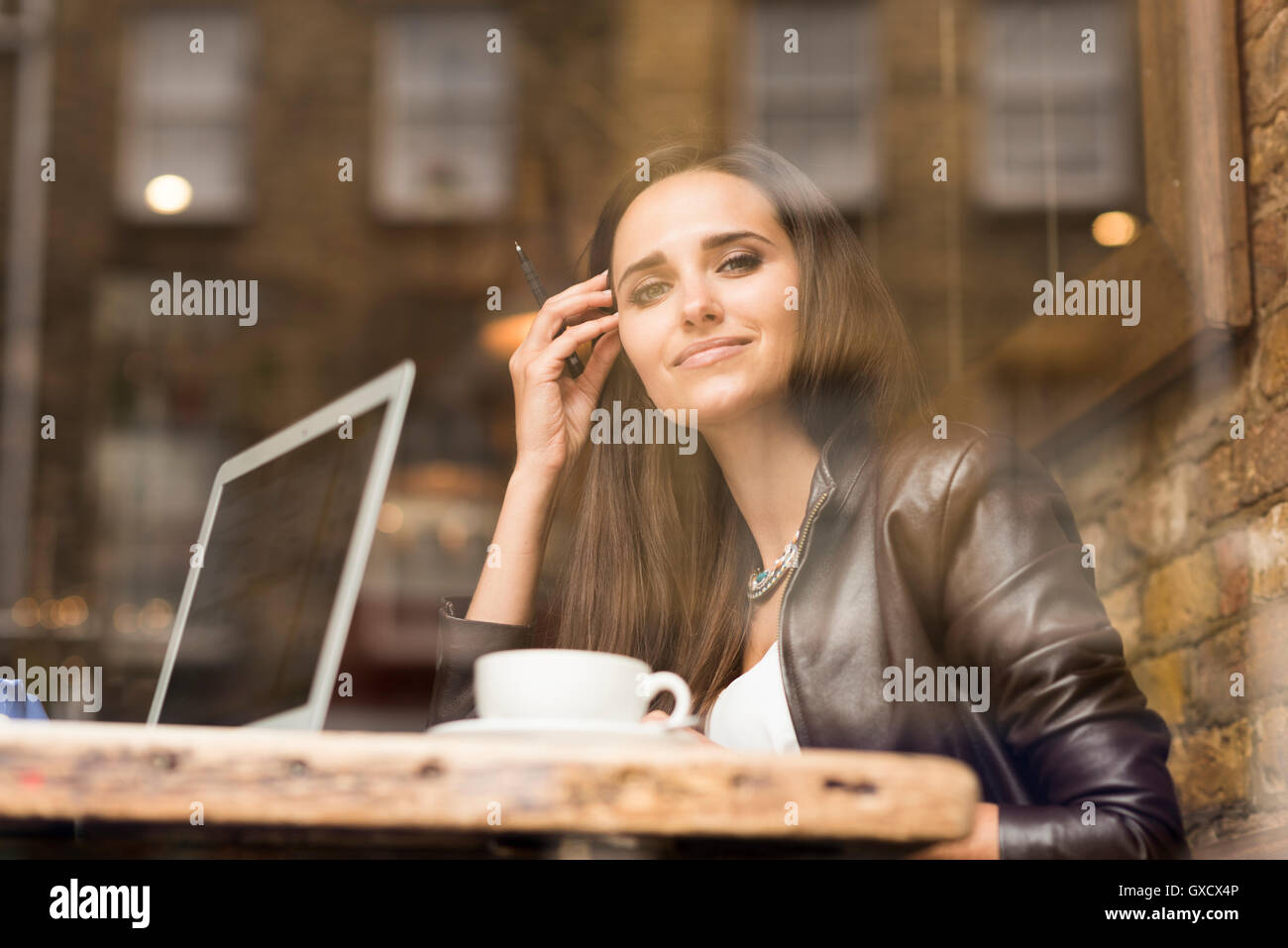 Affichage fenêtre portrait of young businesswoman with laptop in cafe Banque D'Images