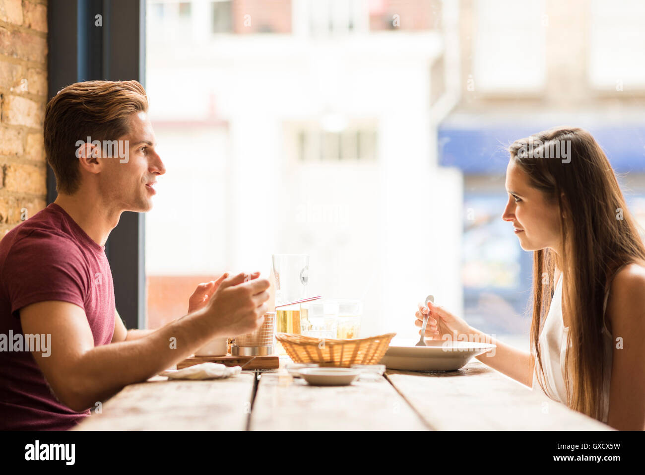Jeune couple chatting tout en mangeant au restaurant Banque D'Images