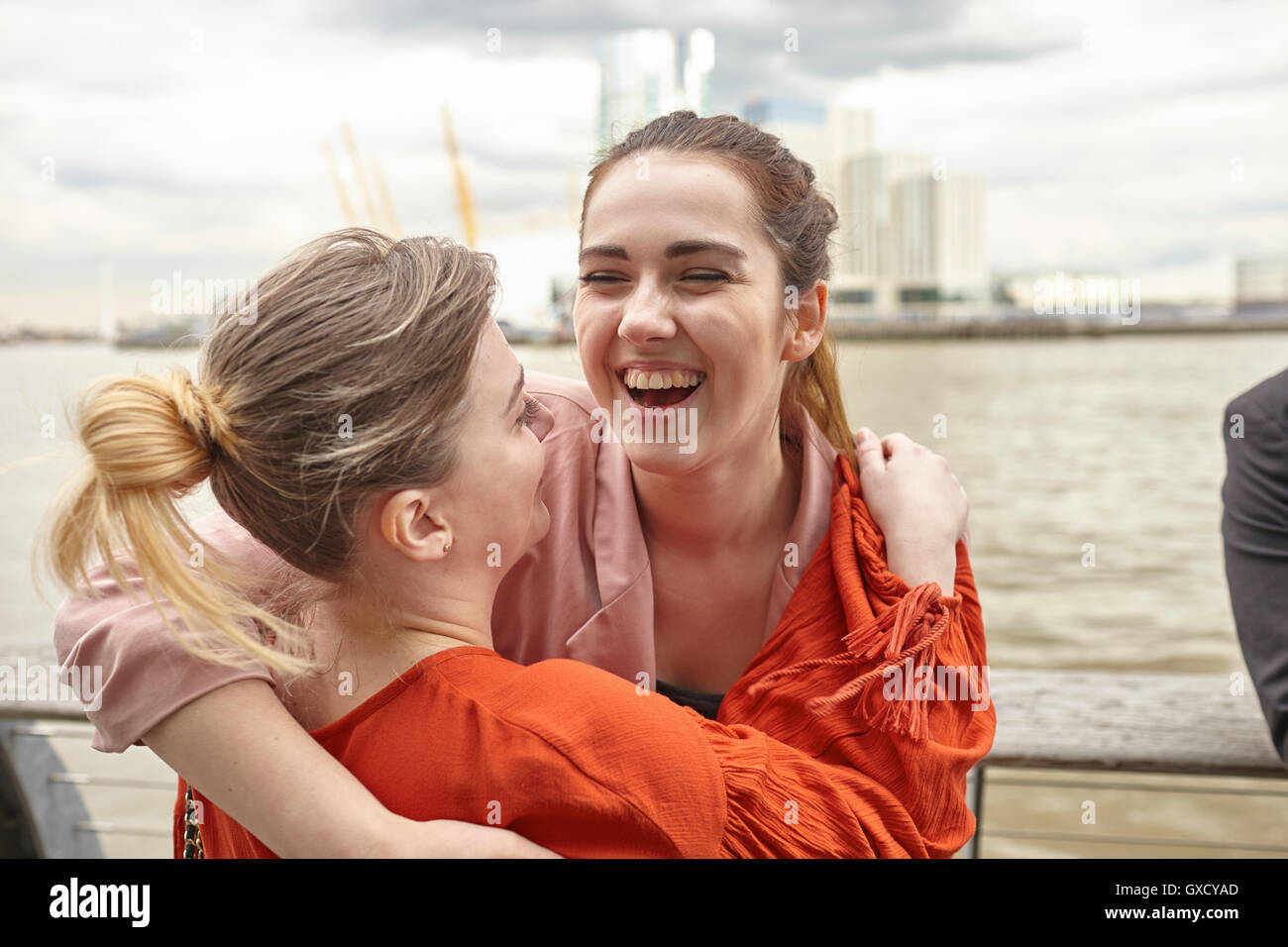 Deux jeunes femmes hugging on waterfront, London, UK Banque D'Images