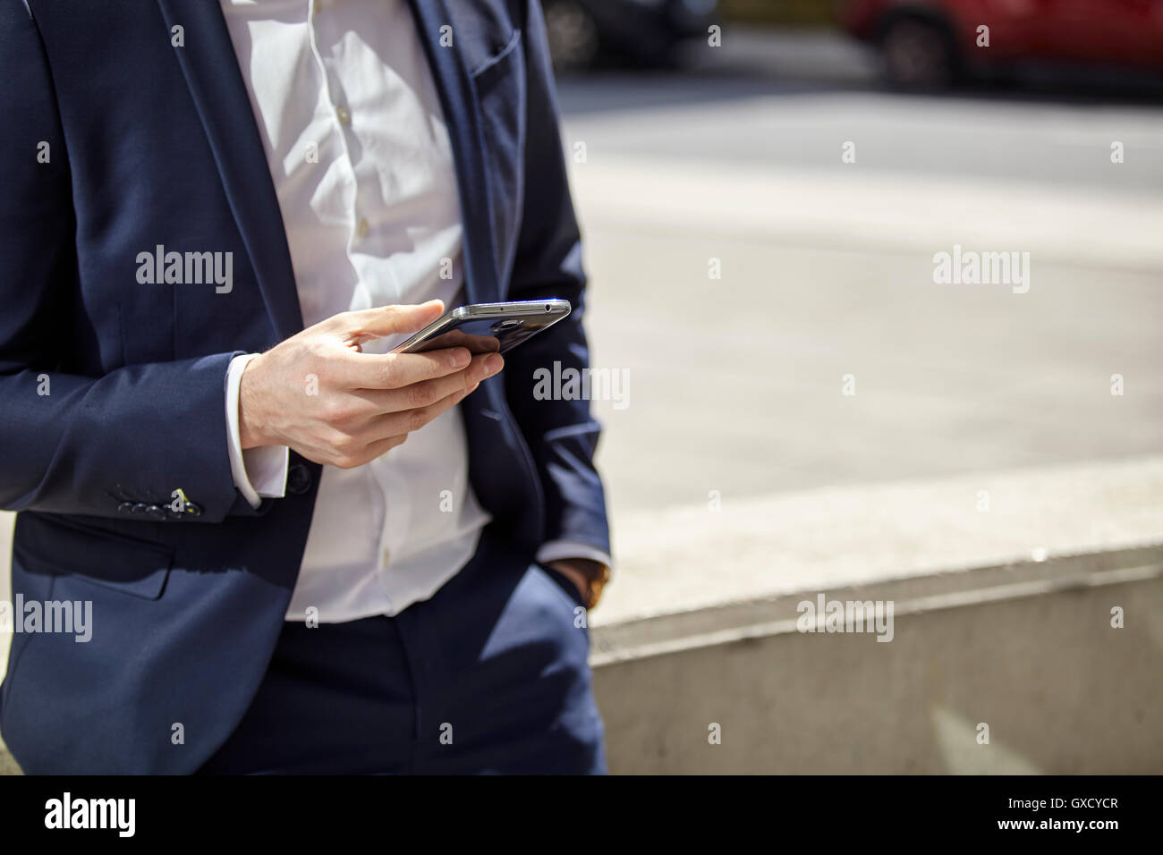 Mid section of businessman texting on smartphone in city Banque D'Images