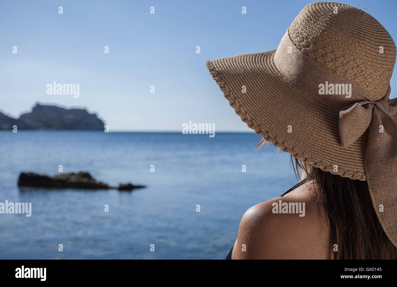 Plus d'épaule de young woman wearing sunhat looking out to sea, Villasimius, Sardaigne, Italie Banque D'Images