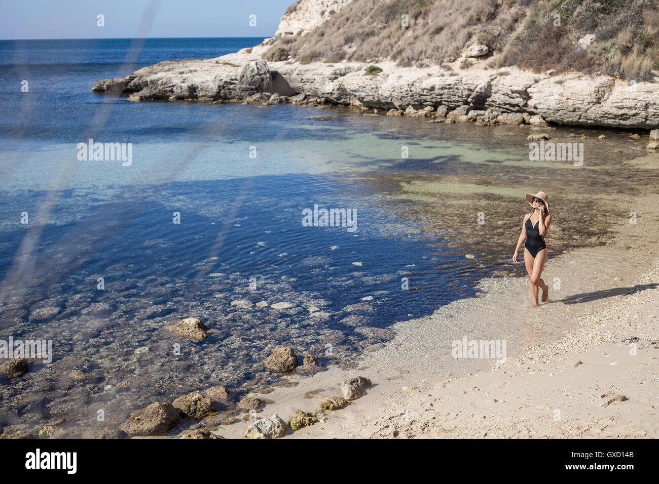 Jeune femme portant un maillot de chatting on smartphone sur plage, Villasimius, Sardaigne, Italie Banque D'Images