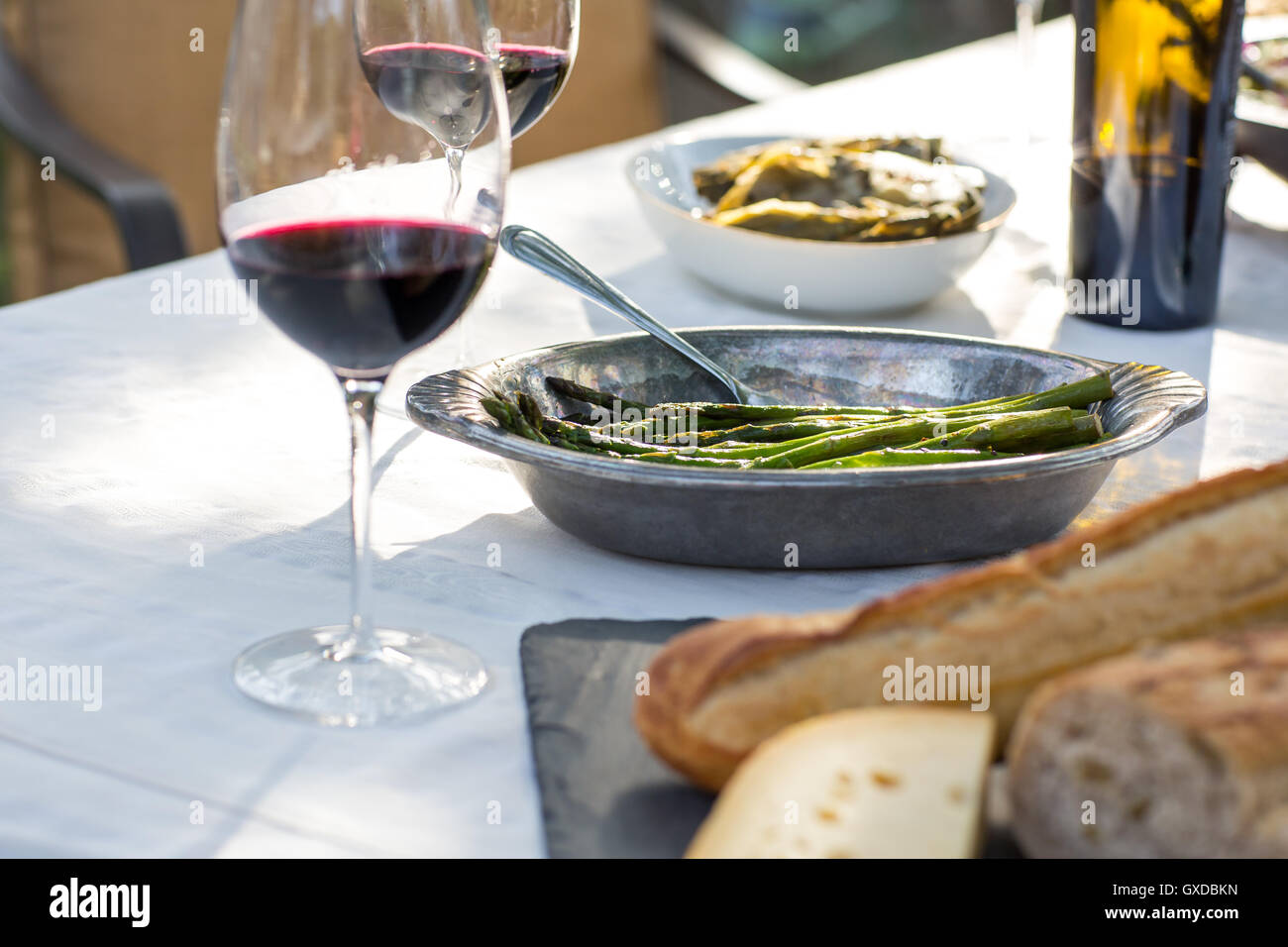 Partie jardin, table avec du vin rouge, plateau de fromages et de haricots verts Banque D'Images