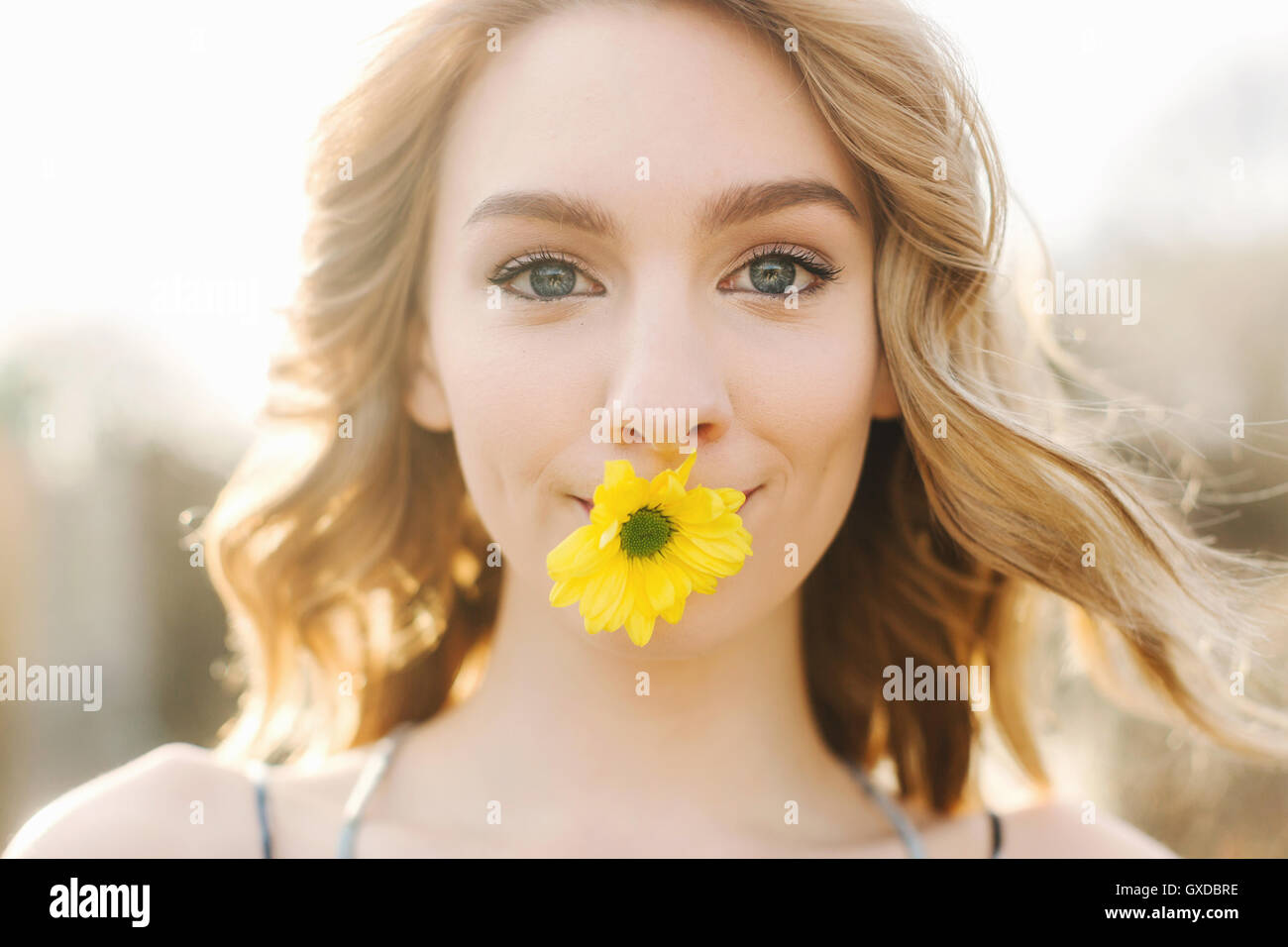 Portrait de jeune femme avec fleur jaune dans la bouche Banque D'Images