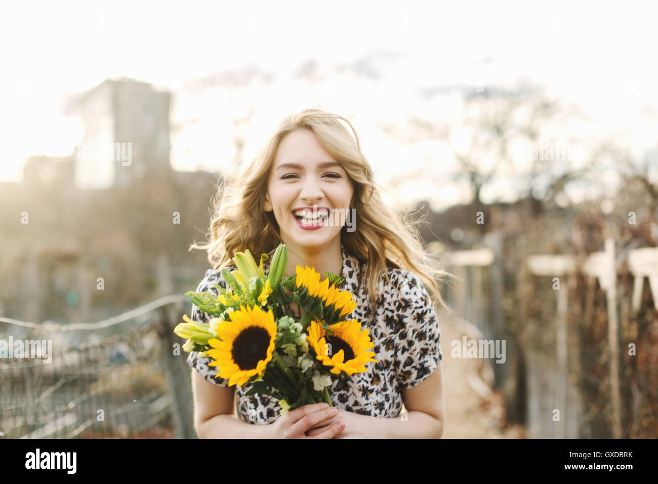 Portrait of young woman holding sunflowers, smiling Banque D'Images