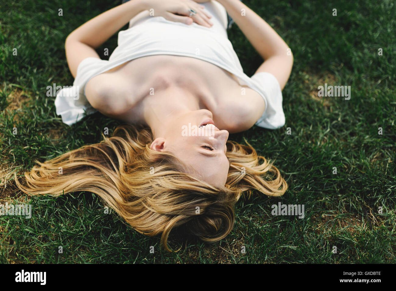 Young woman lying on grass, rire Banque D'Images